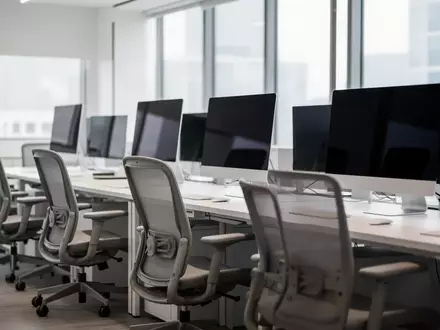 Ein modernes, leeres Büro mit dunklen, ausgeschalteten Computerbildschirmen und ergonomischen Stühlen. - Foto: über boerse-global.de