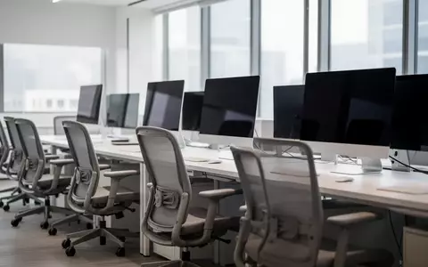 Ein modernes, leeres Büro mit dunklen, ausgeschalteten Computerbildschirmen und ergonomischen Stühlen. - Foto: über boerse-global.de