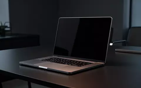 Ein moderner Laptop auf einem dunklen Schreibtisch in einem schwach beleuchteten Raum. - Foto: über boerse-global.de