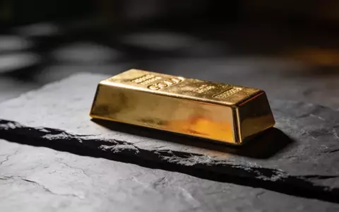 Ein einzelner Goldbarren auf einer dunklen Schieferplatte bei gedimmtem, stimmungsvollem Licht. - Foto: über boerse-global.de