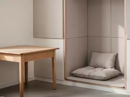 Ein ruhiger, modern gestalteter Rückzugsort in einem Klassenzimmer mit einem Holztisch und einer gemütlichen Sitzecke. - Foto: über boerse-global.de