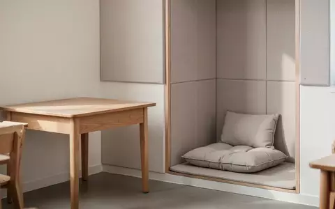 Ein ruhiger, modern gestalteter Rückzugsort in einem Klassenzimmer mit einem Holztisch und einer gemütlichen Sitzecke. - Foto: über boerse-global.de