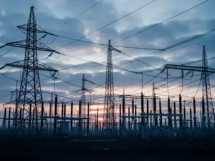 Hochspannungsmasten und elektrische Umspannstation vor einem bewölkten Himmel bei Dämmerung. - Foto: über boerse-global.de