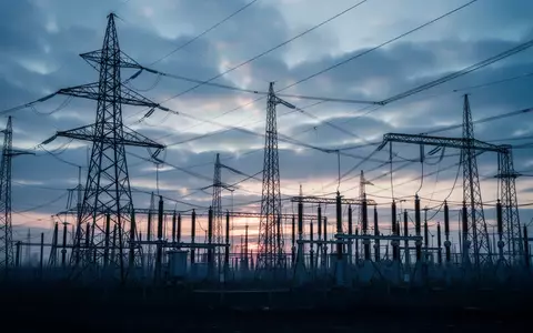 Hochspannungsmasten und elektrische Umspannstation vor einem bewölkten Himmel bei Dämmerung. - Foto: über boerse-global.de