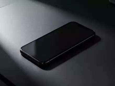 Ein modernes Smartphone liegt mit dunklem Display auf einem minimalistischen Schreibtisch, symbolisch für Cybersicherheit. - Foto: über boerse-global.de
