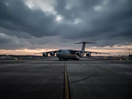 Ein großes Frachtflugzeug steht bei Dämmerung auf dem weitläufigen Rollfeld des Flughafens Leipzig/Halle. - Foto: über boerse-global.de