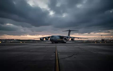 Ein großes Frachtflugzeug steht bei Dämmerung auf dem weitläufigen Rollfeld des Flughafens Leipzig/Halle. - Foto: über boerse-global.de
