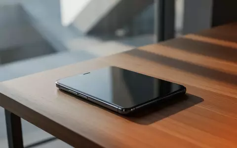 Ein modernes Smartphone auf einem Holztisch in einer minimalistischen Arbeitsumgebung bei natürlichem Licht. - Foto: über boerse-global.de