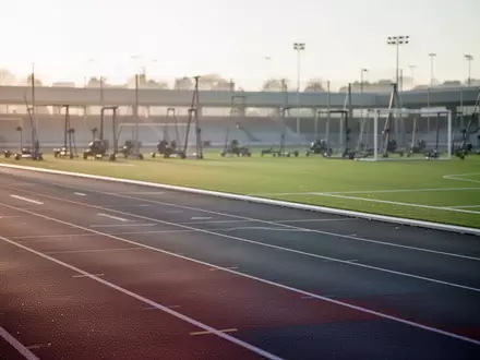 Leere Sportanlage mit Laufbahn und Rasenplatz im sanften Morgenlicht. - Foto: über boerse-global.de
