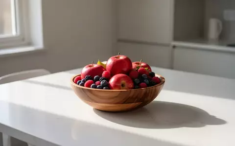 Eine Schale mit frischen Äpfeln und Beeren auf einem minimalistischen Holztisch bei natürlichem Lichteinfall. - Foto: über boerse-global.de