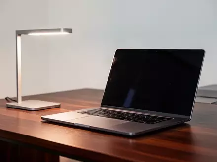 Ein moderner, aufgeräumter Schreibtisch mit einem zugeklappten Laptop und einer Schreibtischlampe in natürlichem Licht. - Foto: über boerse-global.de