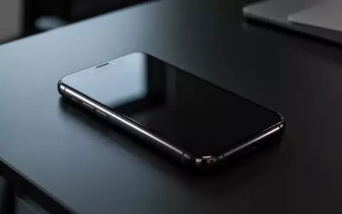 Ein dunkles Smartphone liegt auf einem Schreibtisch; der Bildschirm ist ausgeschaltet und reflektiert das Umgebungslicht. - Foto: über boerse-global.de