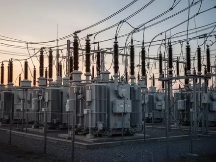Moderne elektrische Umspannstation mit Transformatoren und Stromleitungen vor einem bewölkten Abendhimmel. - Foto: über boerse-global.de