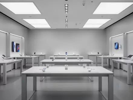 Ein minimalistischer, leerer Verkaufsraum eines Elektronikgeschäfts mit weißen Tischen und indirekter Beleuchtung. - Foto: über boerse-global.de