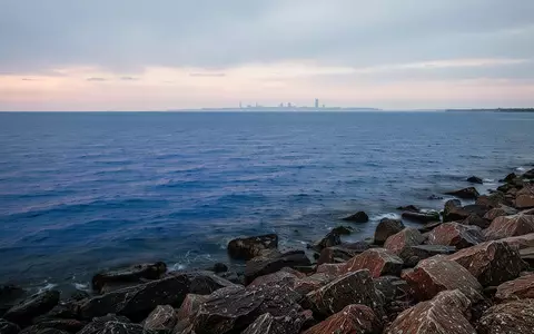 Ein weites, ruhiges Panorama des Ontariosees bei Dämmerung mit felsigem Ufer im Vordergrund und dem Horizont im Hintergrund. - Foto: über boerse-global.de