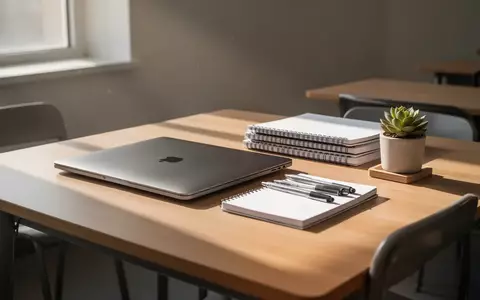 Ein aufgeräumter Schreibtisch in einem modernen Klassenzimmer mit einem geschlossenen Laptop und Schreibutensilien bei Tageslicht. - Foto: über boerse-global.de