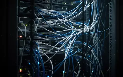Ein technischer Serverraum mit leuchtenden Glasfaserkabeln in einer düsteren, angespannten Atmosphäre. - Foto: über boerse-global.de