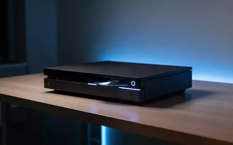 Eine moderne Spielkonsole mit optischem Laufwerk auf einem minimalistischen Schreibtisch bei dezenter blauer Beleuchtung. - Foto: über boerse-global.de