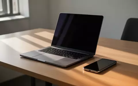 Ein minimalistischer Büroarbeitsplatz mit einem Laptop und einem Smartphone auf einem Holztisch bei natürlichem Licht. - Foto: über boerse-global.de