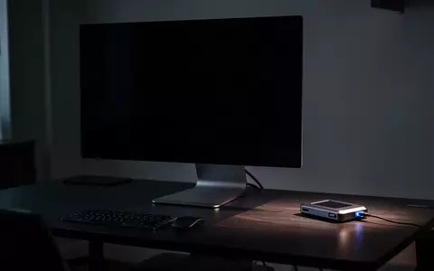 Ein dunkler Schreibtisch mit einem ausgeschalteten Computerbildschirm und einer Hardware-Krypto-Wallet in einer düsteren Büroumgebung. - Foto: über boerse-global.de