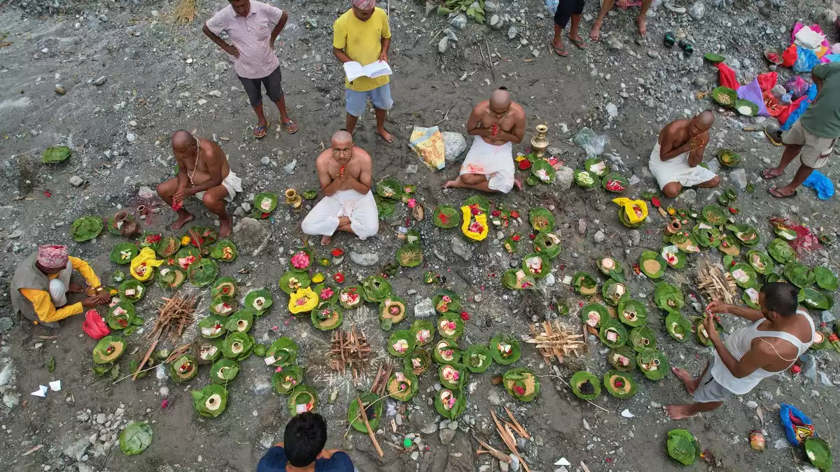 Menschen, deren Angehörige nach den Sturzfluten weiterhin vermisst werden, vollziehen am Ufer des angeschwollenen Trishuli-Flusses im nepalesischen Distrikt Nuwakot Rituale im Anschluss an symbolische Bestattungszeremonien. - Bild: Rajesh Kumar Singh/AP/dpa