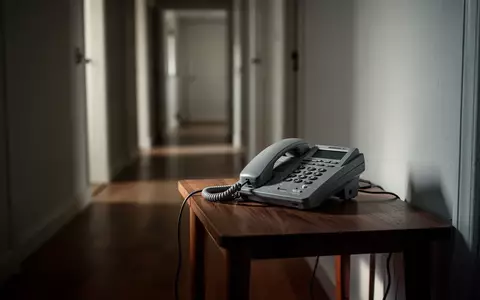 Ein klassisches Festnetztelefon auf einem Holztisch in einem flurartigen Wohnbereich. - Foto: über boerse-global.de