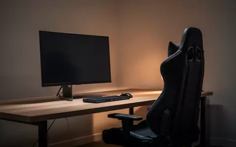 Ein dunkler, minimalistischer Arbeitsplatz mit einem ergonomischen Stuhl und einem ausgeschalteten Computerbildschirm. - Foto: über boerse-global.de