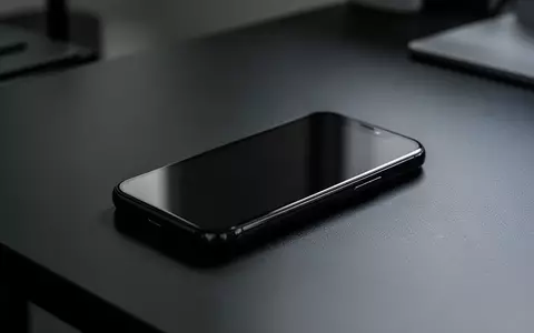 Ein unbenutztes Smartphone liegt auf einem dunklen Büroschreibtisch, der Bildschirm ist dunkel und zeigt keine Inhalte. - Foto: über boerse-global.de