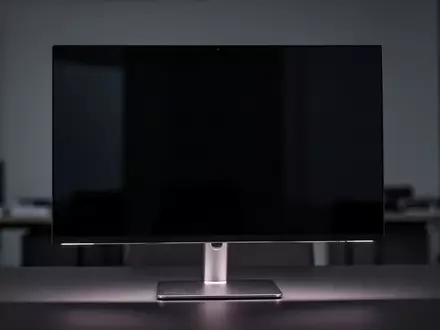 Ein moderner, ausgeschalteter High-End-Monitor auf einem minimalistischen Schreibtisch in einem dunklen Studio. - Foto: über boerse-global.de