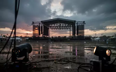 Eine leere Konzertbühne auf einem verregneten Festivalgelände in der Abenddämmerung. - Foto: über boerse-global.de