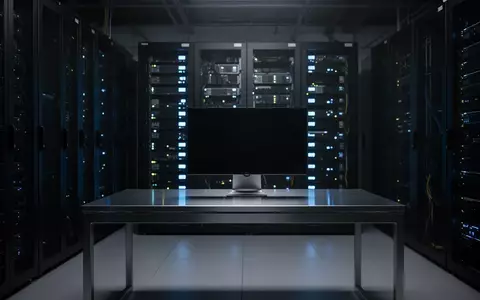 Ein dunkler, moderner Serverraum mit leuchtenden blauen Status-LEDs und einem unbenutzten, ausgeschalteten Arbeitsplatz. - Foto: über boerse-global.de