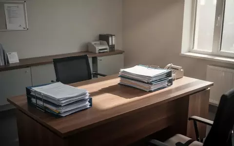 Leeres Büro mit Aktenordnern auf einem Schreibtisch, das die angespannte finanzielle Lage in der Pflege symbolisiert. - Foto: über boerse-global.de