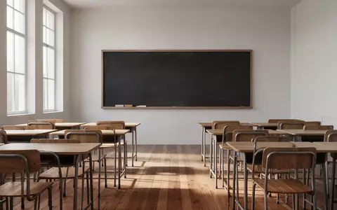 Leeres Klassenzimmer mit Holztischen und einer leeren Tafel in einem hellen, sonnendurchfluteten Raum. - Foto: über boerse-global.de
