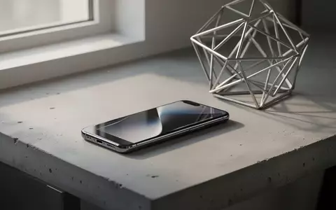 Ein modernes Smartphone auf einem minimalistischen Schreibtisch neben einer abstrakten Metallskulptur. - Foto: über boerse-global.de