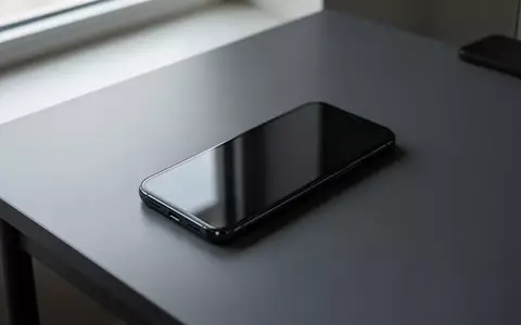 Ein modernes Smartphone liegt auf einem dunklen Schreibtisch mit ausgeschaltetem Bildschirm. - Foto: über boerse-global.de