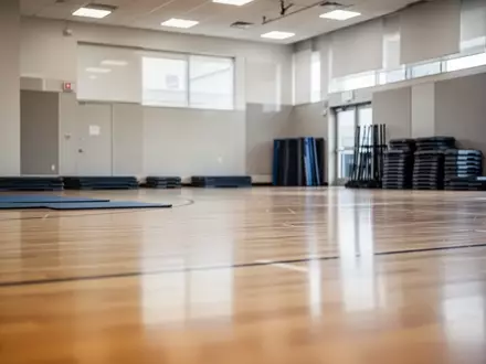 Leere Sporthalle mit aufgeräumten Sportgeräten und einfallendem Tageslicht. - Foto: über boerse-global.de