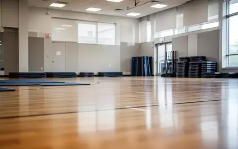 Leere Sporthalle mit aufgeräumten Sportgeräten und einfallendem Tageslicht. - Foto: über boerse-global.de
