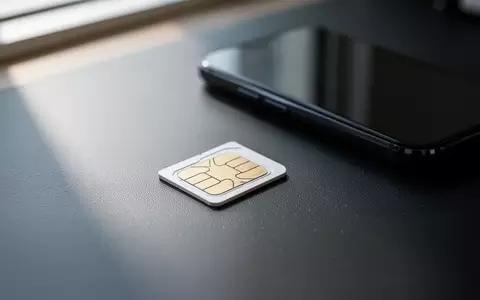 Eine einzelne SIM-Karte liegt auf einem dunklen Schreibtisch neben einem unscharfen Smartphone. - Foto: über boerse-global.de