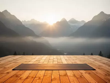 Leere Holzplattform für Yoga vor einer alpinen Bergkulisse im sanften Licht des frühen Morgens. - Foto: über boerse-global.de