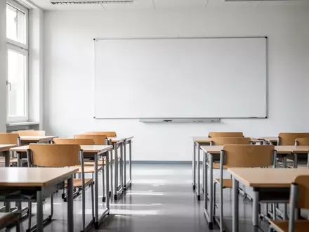Ein leerer, modern gestalteter Klassenraum mit hellen Holzmöbeln und einer leeren weißen Tafel bei Tageslicht. - Foto: über boerse-global.de