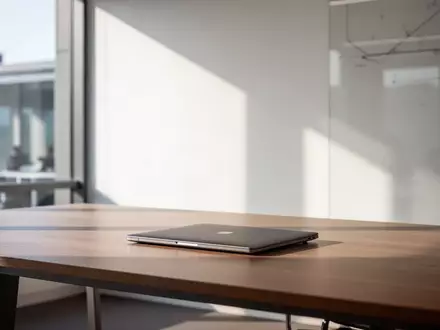 Minimalistischer Büroarbeitsplatz mit geschlossenem Laptop und natürlichem Lichteinfall in einem modernen Gebäude. - Foto: über boerse-global.de