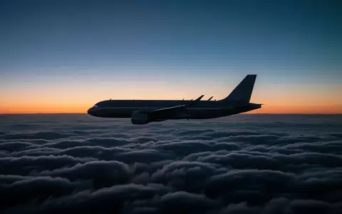 Ein Passagierflugzeug fliegt in der Dämmerung über einer dichten Wolkendecke. - Foto: über boerse-global.de