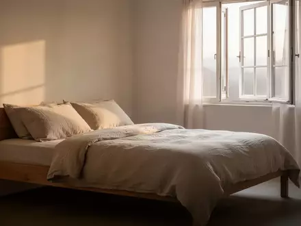 Ein minimalistisch eingerichtetes, helles Schlafzimmer mit natürlichem Tageslicht und ordentlich bezogenem Bett. - Foto: über boerse-global.de
