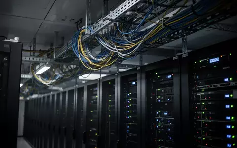 Dunkler Serverraum mit Netzwerkschränken und beleuchteten Kabeltrassen als Symbol für Cybersicherheit. - Foto: über boerse-global.de