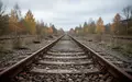Verwitterte Bahngleise mit rostigen Schienen in einer vernachlässigten Industrielandschaft bei bewölktem Himmel. - Foto: über boerse-global.de