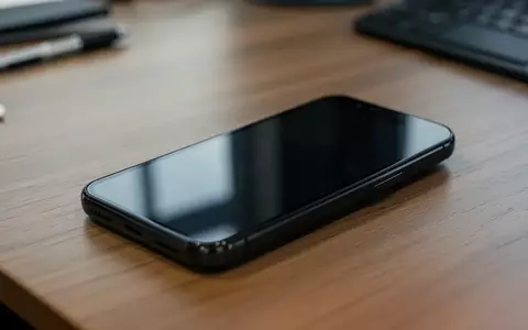 Ein dunkles Android-Smartphone liegt auf einem Holztisch in einer Büroumgebung. - Foto: über boerse-global.de