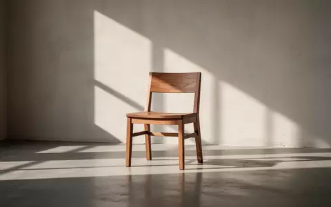 Ein leerer Holzstuhl in einem sonnendurchfluteten, minimalistischen Raum mit langen Schatten an der Wand. - Foto: über boerse-global.de