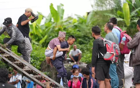 Ein Mann wird im Katastrophengebiet in Nepal von einem Polizisten auf dem Rücken getragen. - Foto: Rajesh Kumar Singh/AP/dpa