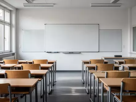 Ein leerer Klassenraum in einer öffentlichen Schule mit leeren Holztischen und einer weißen Tafel bei Tageslicht. - Foto: über boerse-global.de