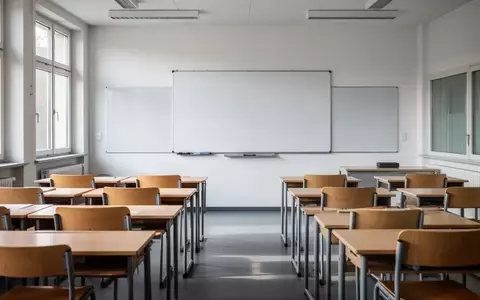Ein leerer Klassenraum in einer öffentlichen Schule mit leeren Holztischen und einer weißen Tafel bei Tageslicht. - Foto: über boerse-global.de
